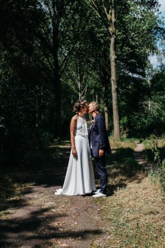 Sportief bruidspak, vrouwelijk glanzend  met langer jasje en ronde mouwtjes gemaakt voor huwelijk van Anne Fleur